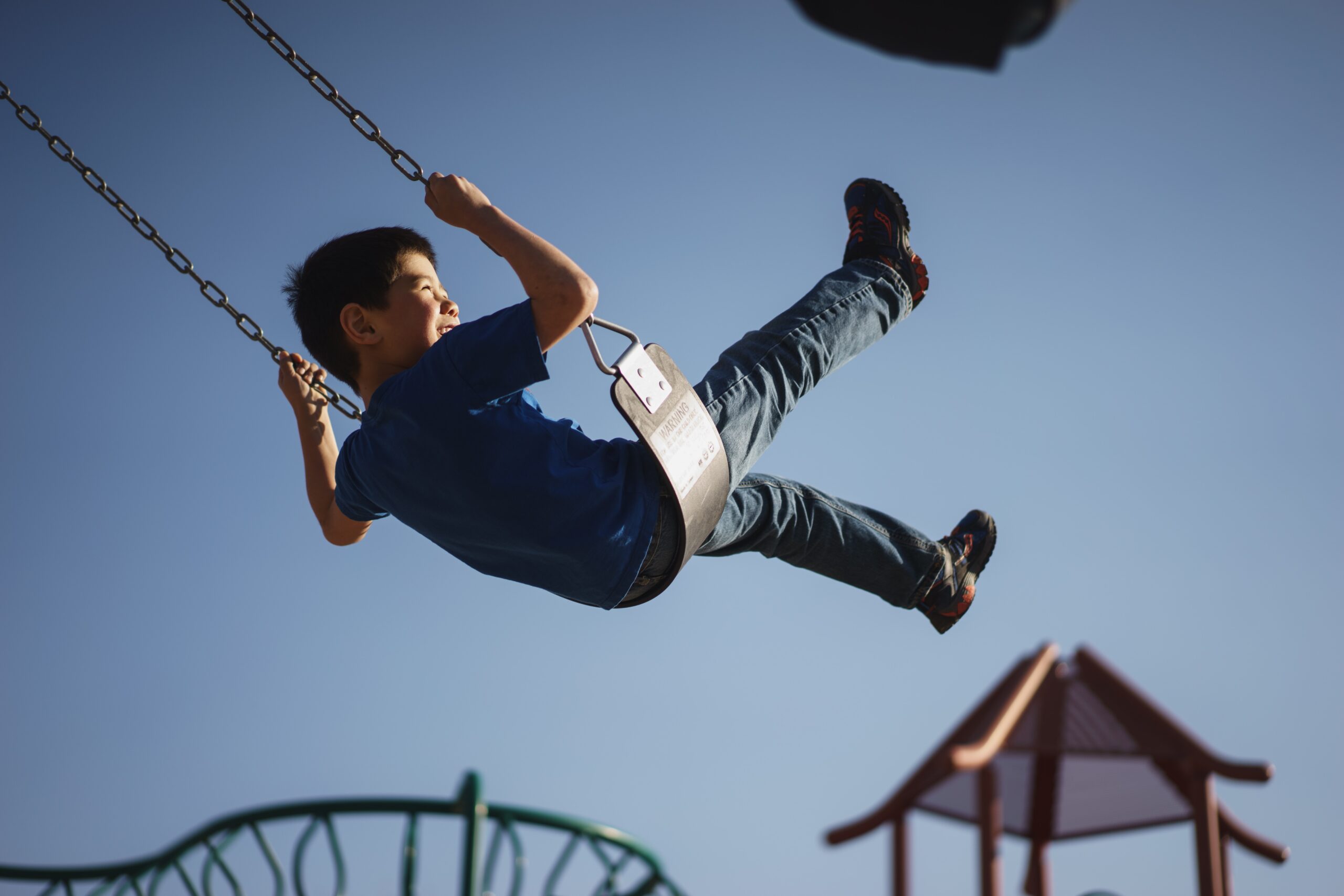 Schoolboy playing in a swing swing in the school